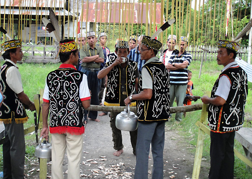 Vor dem Teilen des Balkens um ins Dayak-Taman-Langhaus zum Gawai in Melapi zu kommen muss erst einmal ein Schluck Saguer in den Rachen und auf den Boden.